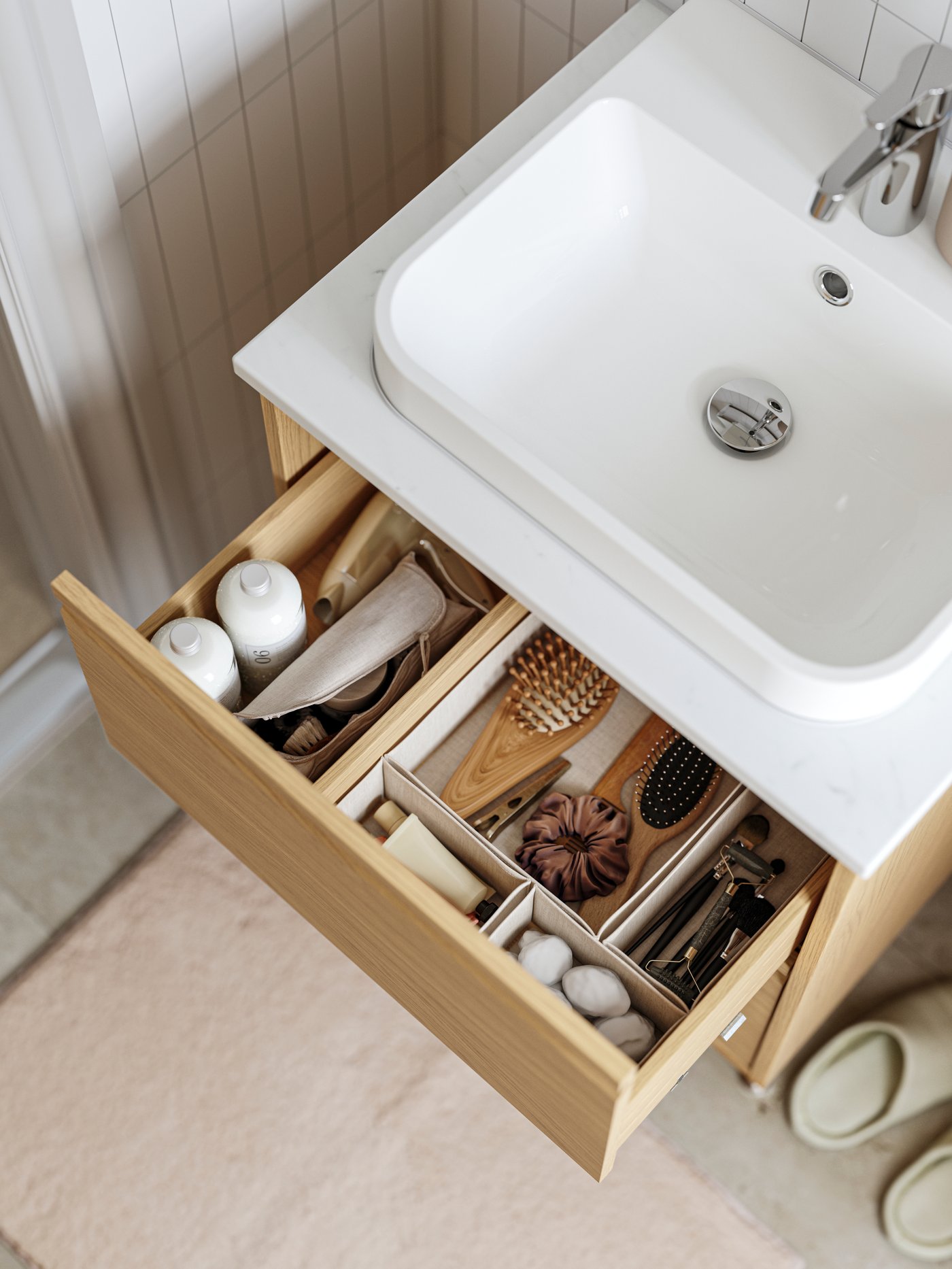 Un lavabo ÄNGSJÖN con cassetti presenta un cassetto aperto e al suo interno sono presenti degli organizer per cassetti BOLLÖSUND di colore beige.