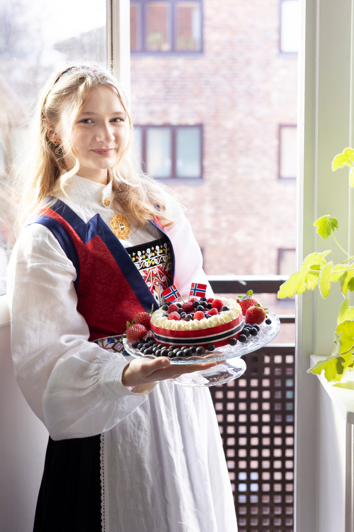 A woman holds a cake plate with sponge cake for May 17th.