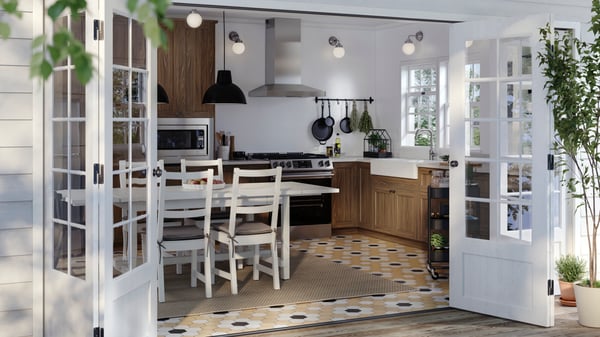 A sunny kitchen with walnut-effect ENKÖPING doors on the cabinets and a white table with chairs around it.