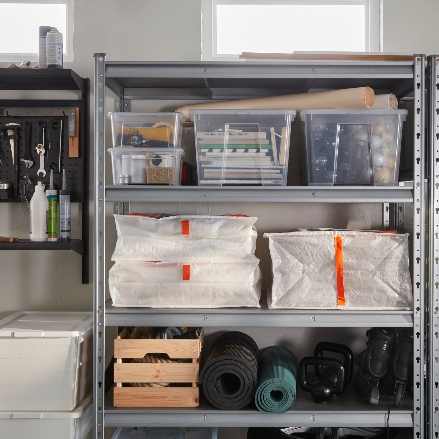 PÄRKLA storage cases filled with cushions and arranged on a metal shelving unit with boxes and equipment.