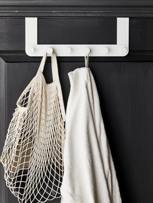 A towel and a mesh bag hang on two circular hooks of a white-coated steel ENUDDEN hanger for door.