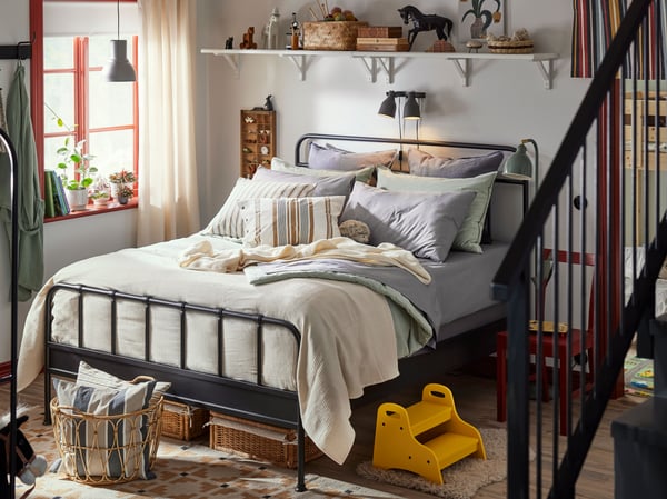 Family bedroom with STJÄRNÖ classic bedframe in anthracite, with bedding and lots of pillows in blue and white.
