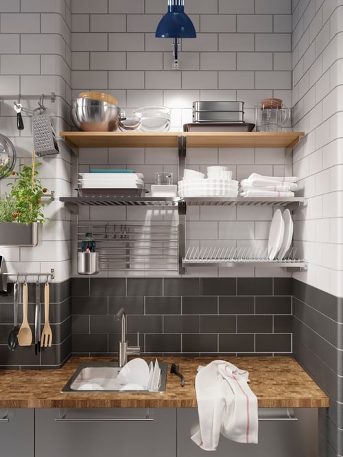 Modern kitchen with a wall storage unit featuring open shelves, a magnetic knife holder, a dish drainer, serving bowls, a grater and tea towels.