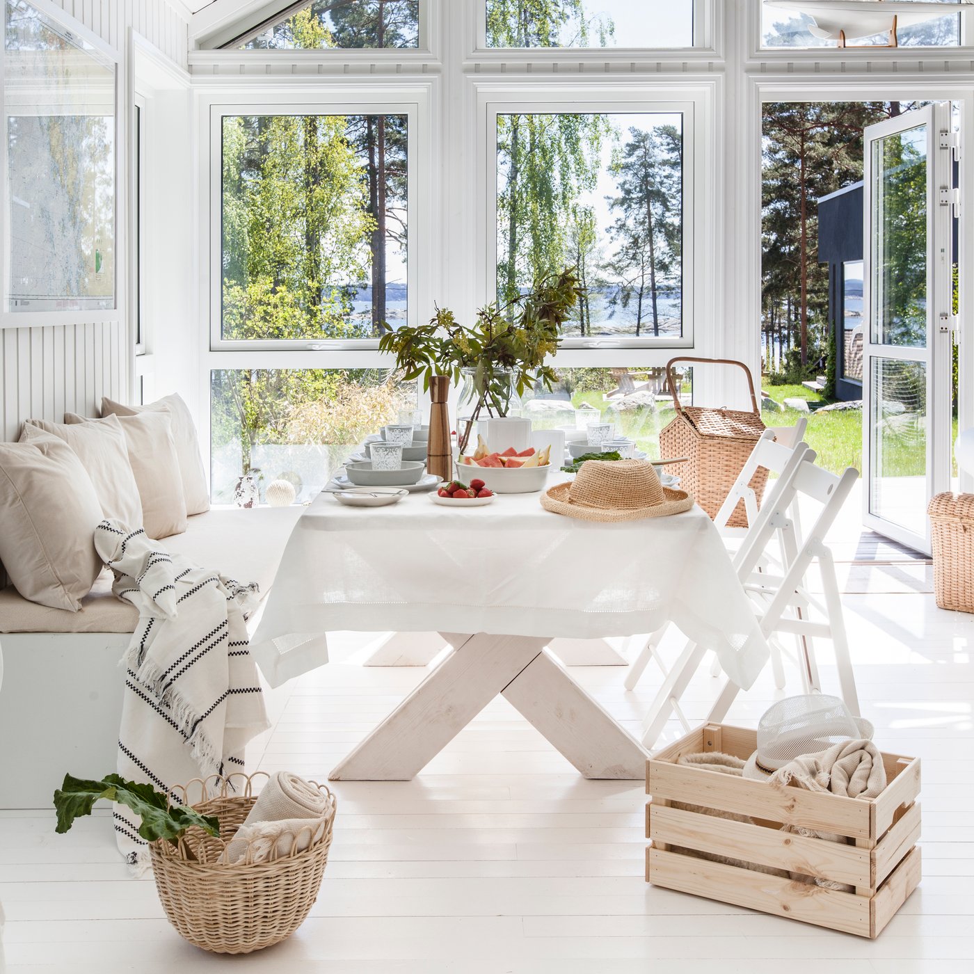 Kuva kesämökin ruokailutilasta, jossa on iso ruokapöytä ja säilytyspenkki.