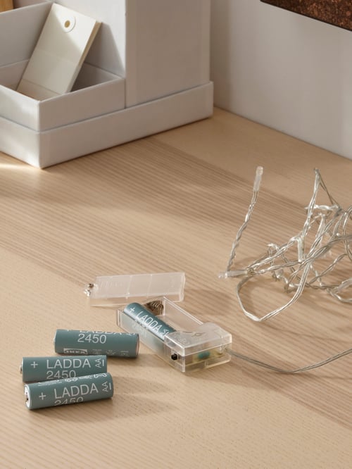Detaliu pe birou din lemn pentru spațiul de lucru, cu lanț de iluminat LED și 4 baterii reîncărcabile, de dimensiuni AA, 1,2V și 2450 mAh.
