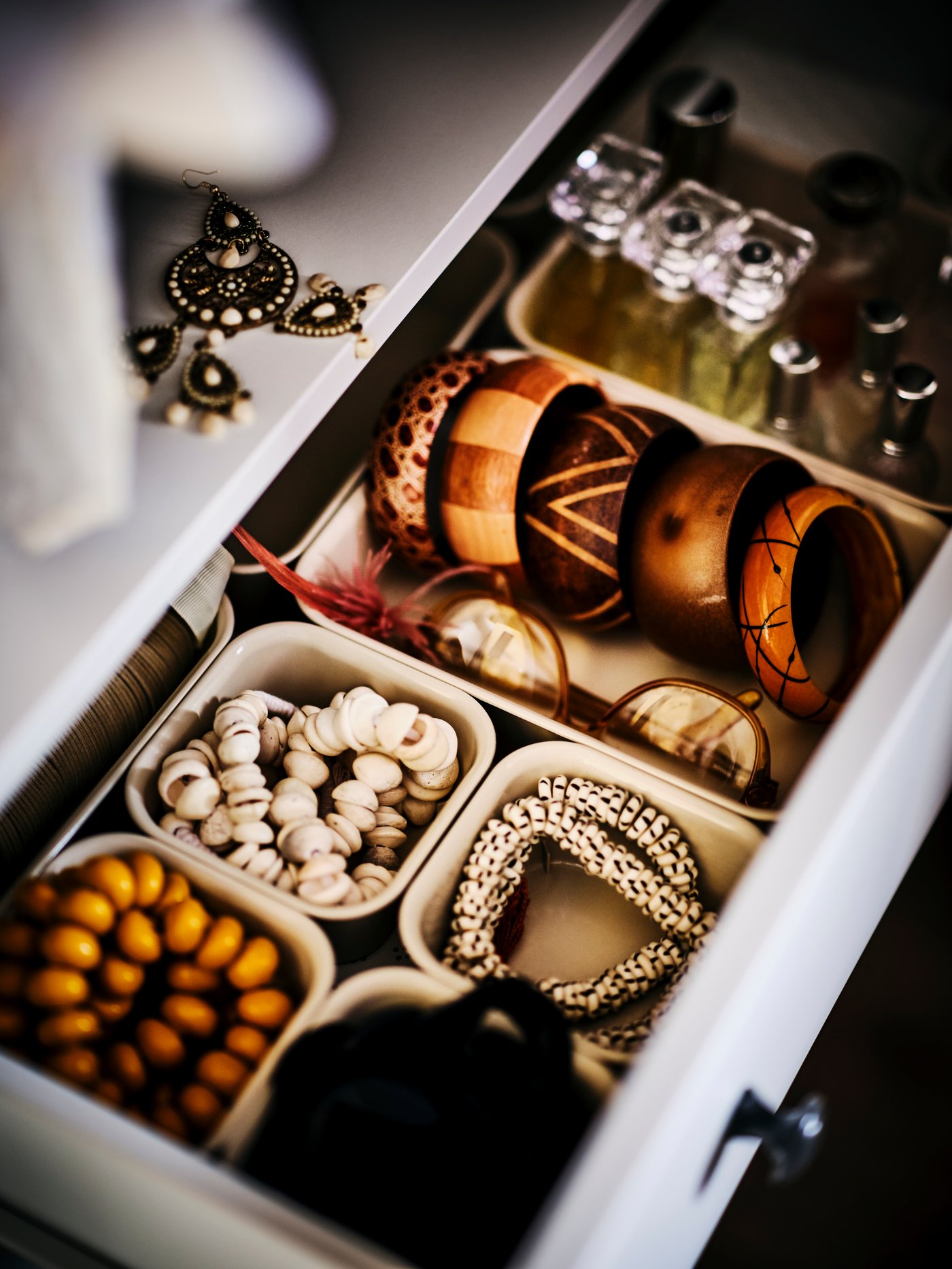 En öppen byrålåda innehållandes småförvaring med smycken i.