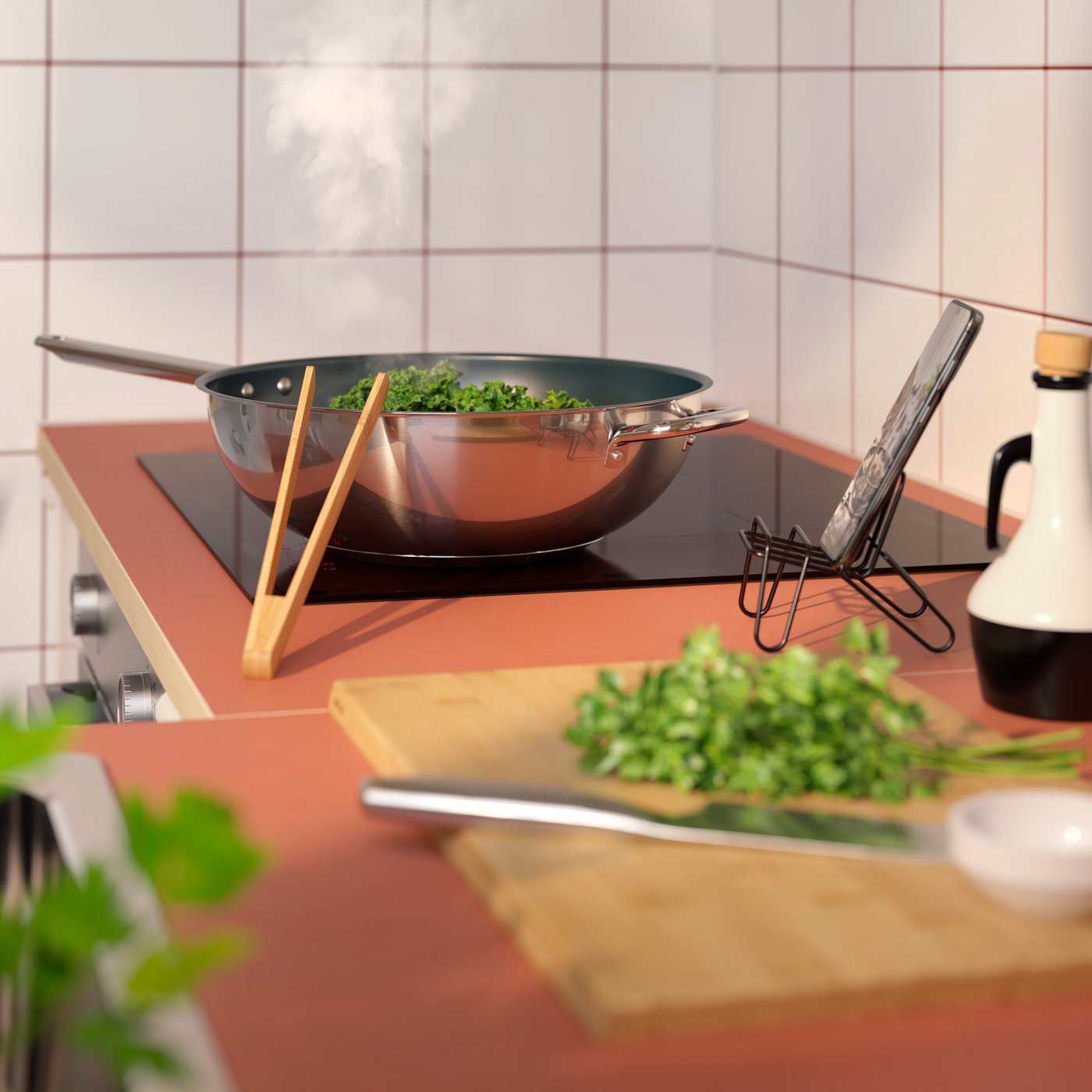An EKBACKEN worktop with a wooden chopping board and knife, and a hob with an IKEA365+ non-stick wok in stainless steel.