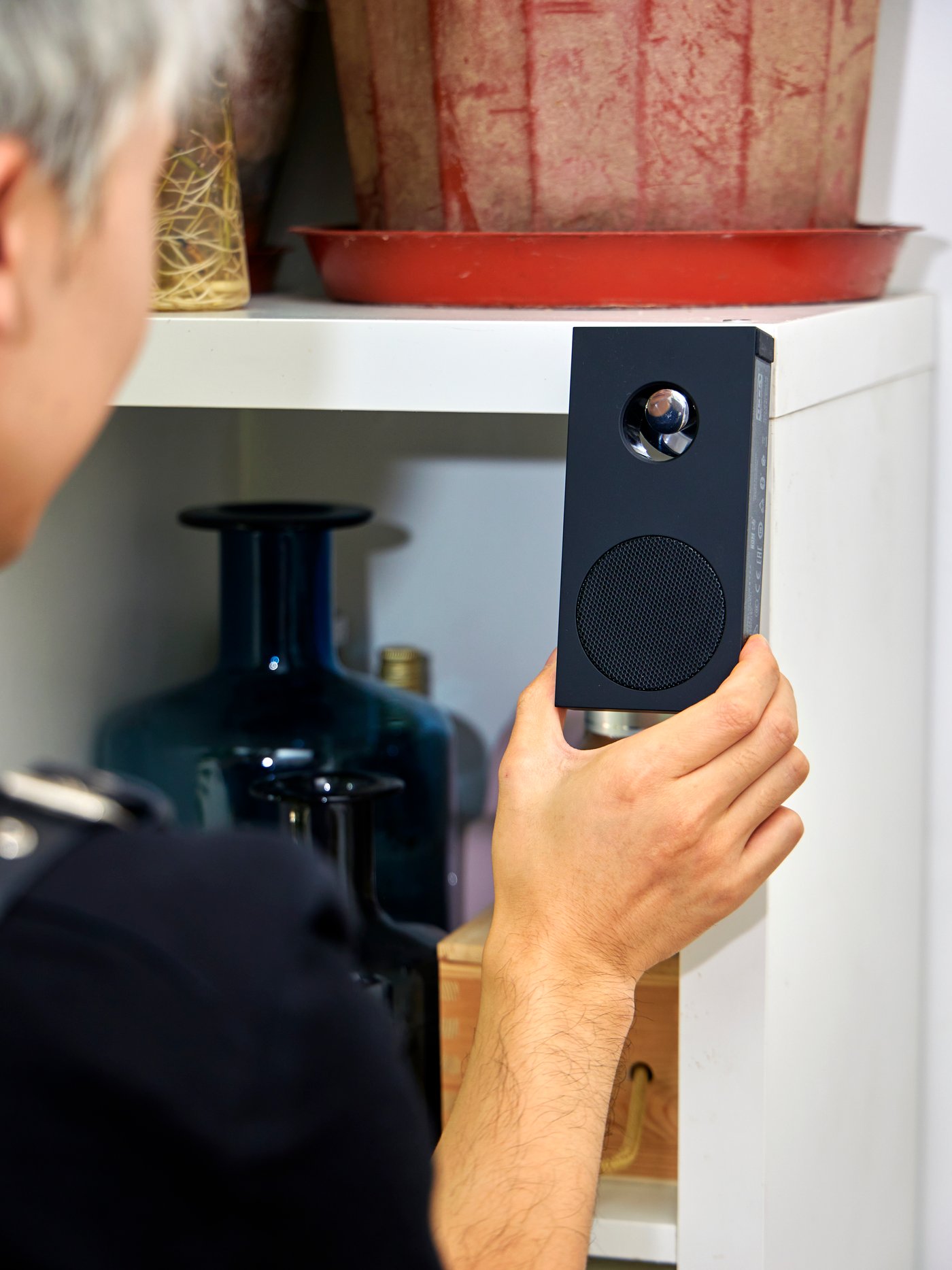 A man is holding an ENEBY portable bluetooth speaker.