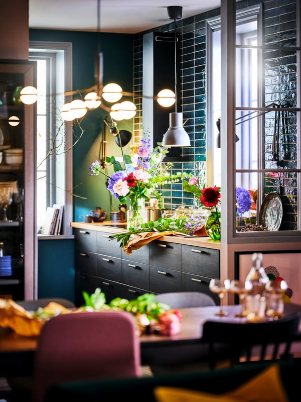A STORSLINGA LED 8-armed chandelier illuminating a dining area with an ASKERSUND dark brown kitchen in the background.