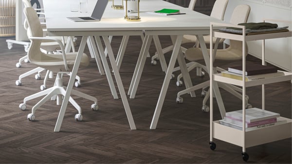 Een vernieuwde kantoorruimte met vier witte TROTTEN-bureaus die bij elkaar zijn geplaatst, gecombineerd met beige/witte LÅNGFJÄLL-vergaderstoelen.