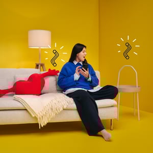 Person on a sofa in a yellow room using a phone.