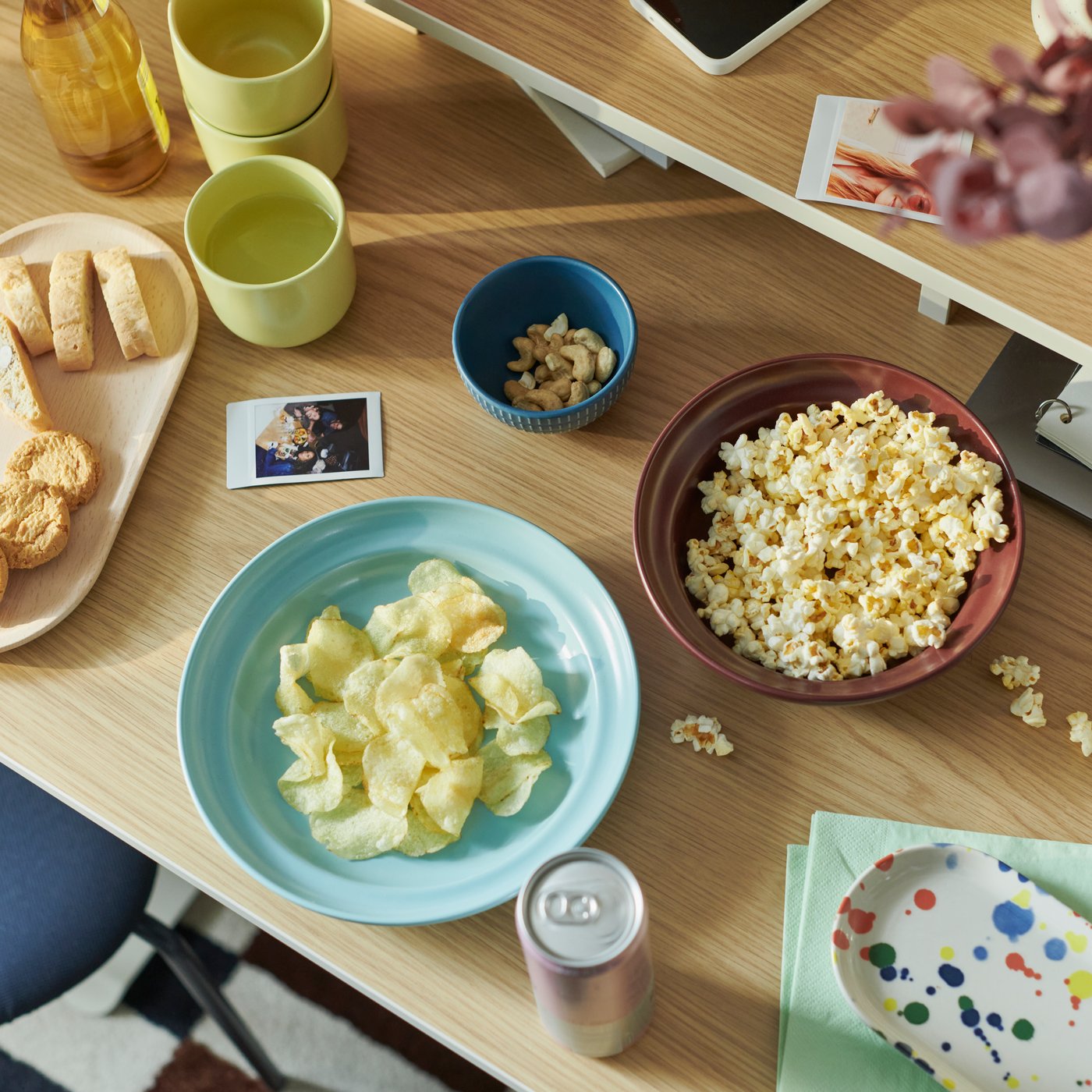A TRAVSPORT table top surface with a colourful SPJUTLILJA 3-piece serving set holding snacks and refreshments.