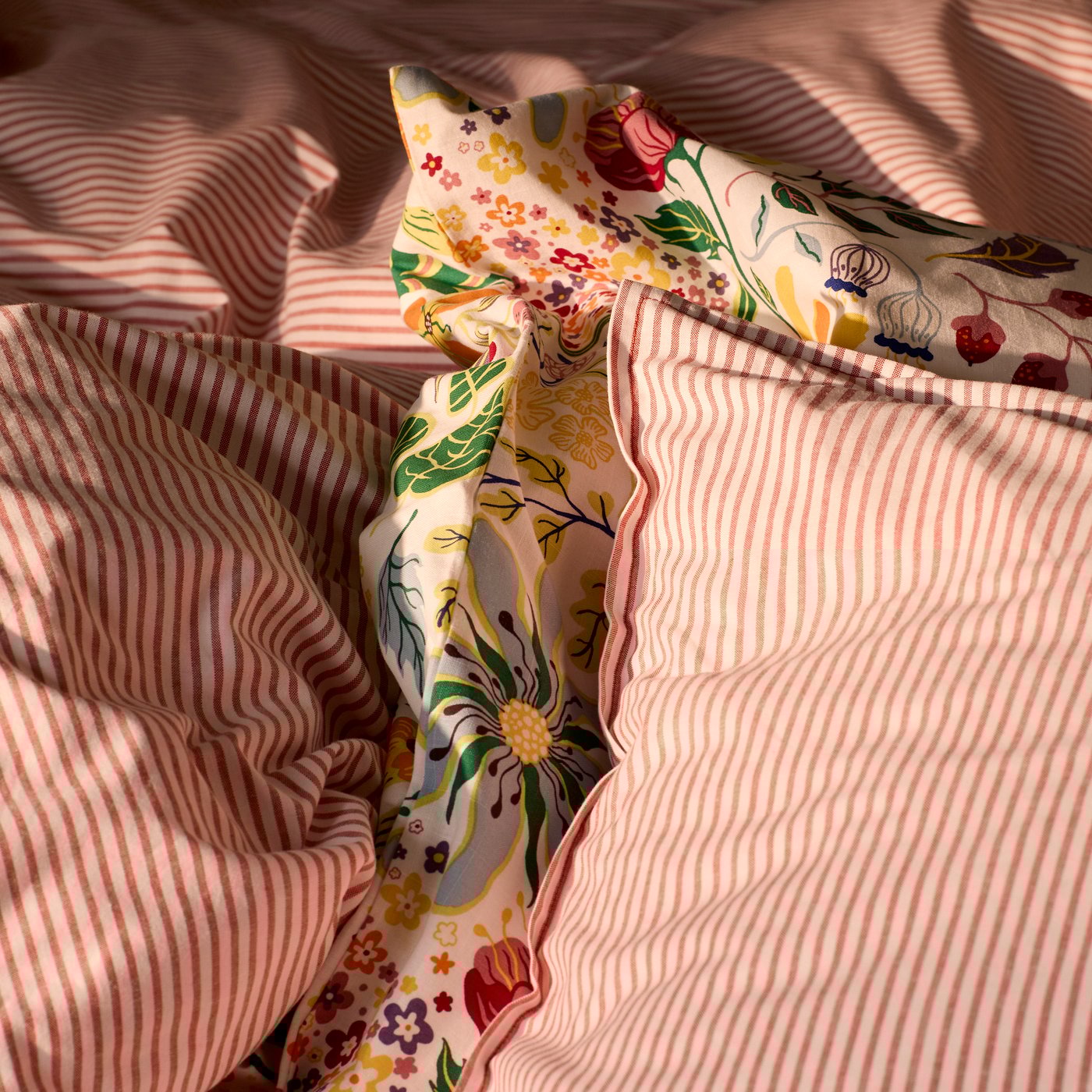 A close-up of the striped SOLFIBBLA and the floral patterned BRUDKRUSBÄR duvet covers and pillow cases.