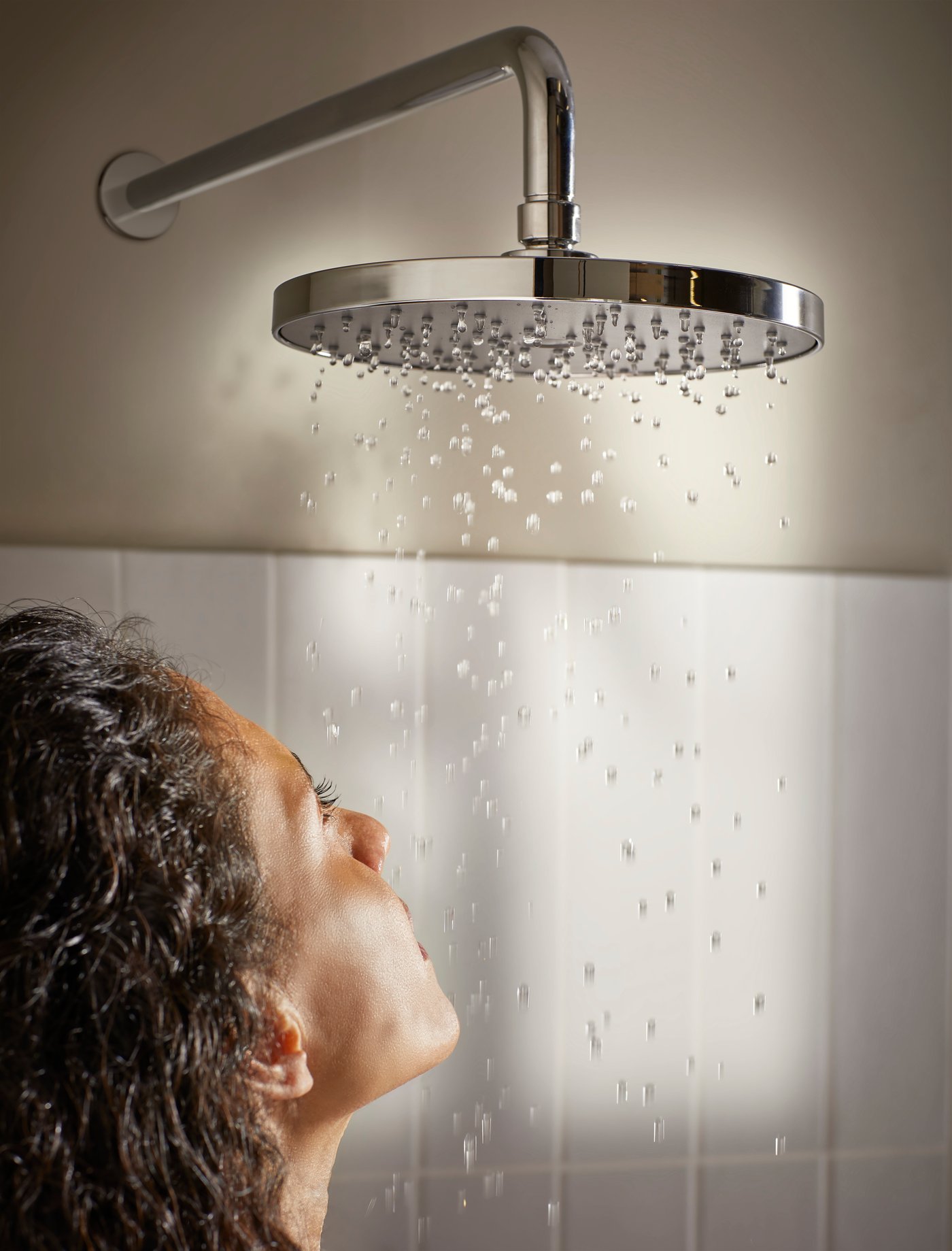 A chrome-plated BROGRUND single-spray showerhead with arm in the bathroom