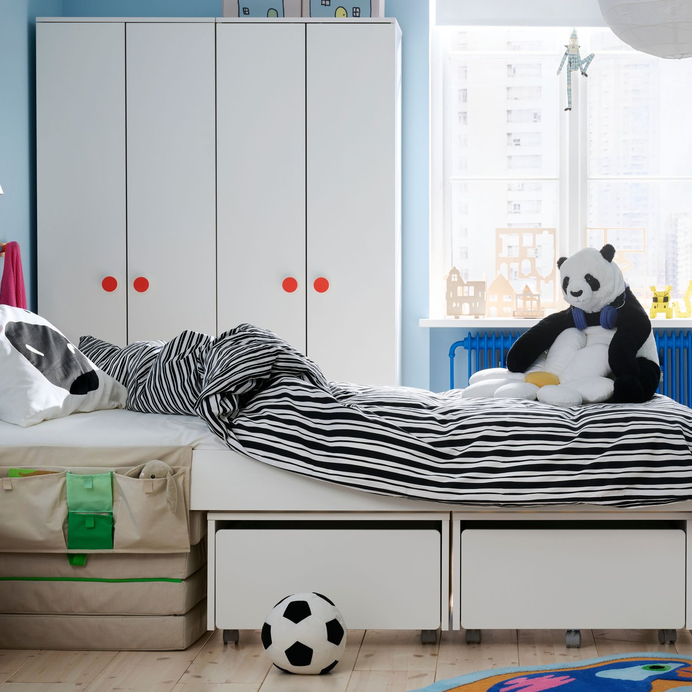 A children’s room with the SLÄKT bed in the middle made up with NATTHÄGER bedding, Wardrobes and window in background.