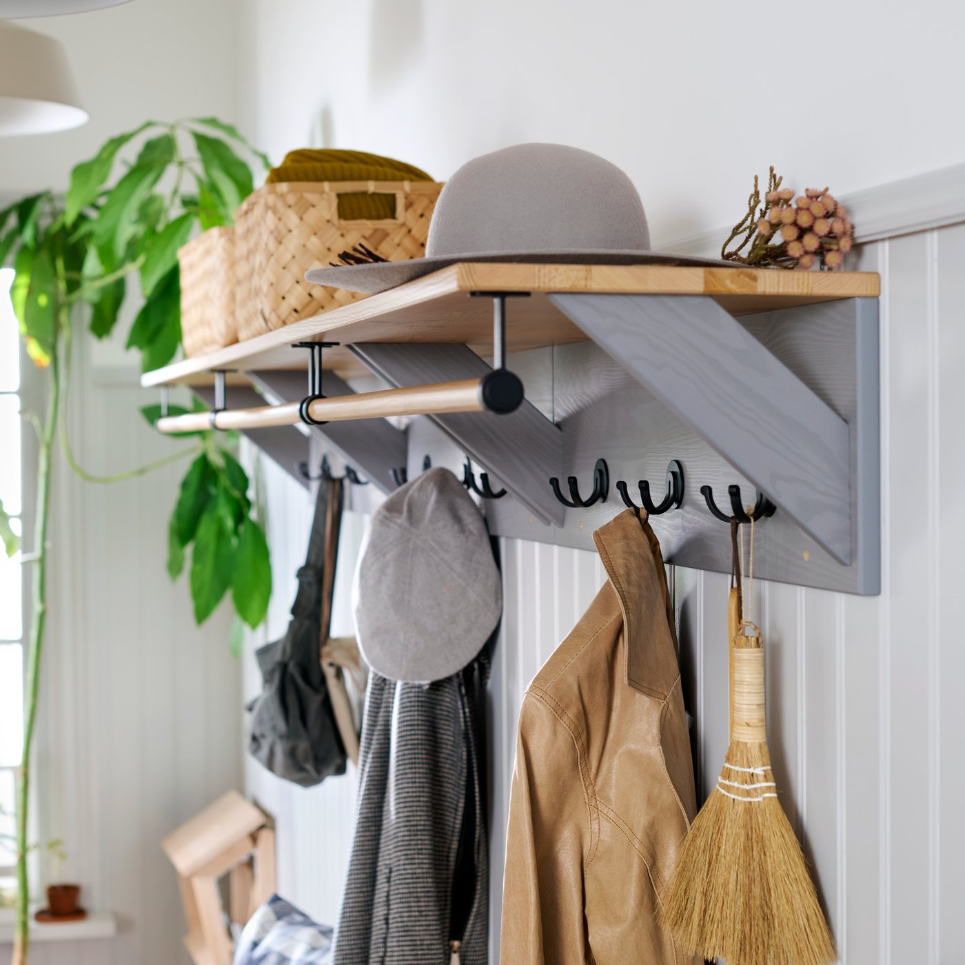 Close-up of three KALLSÖ hat racks in a row, with baskets and a hat on top shelf and clothes hanging on the hooks.