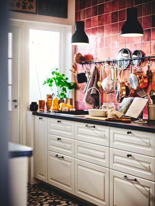 Modern kitchen with dark grey backsplash, black worktop, and base cabinets with traditional white wooden drawer fronts.