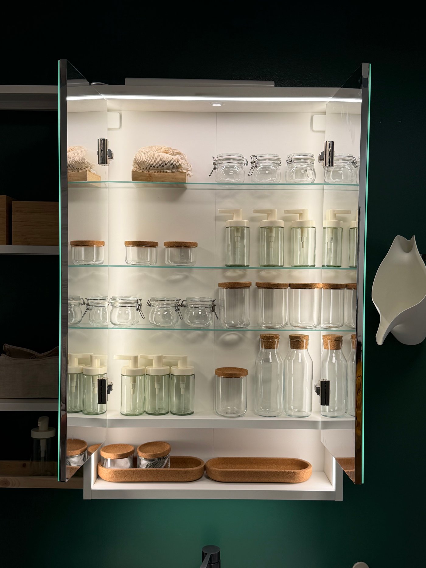 Des bocaux en verre dans un meuble haut de salle de bain