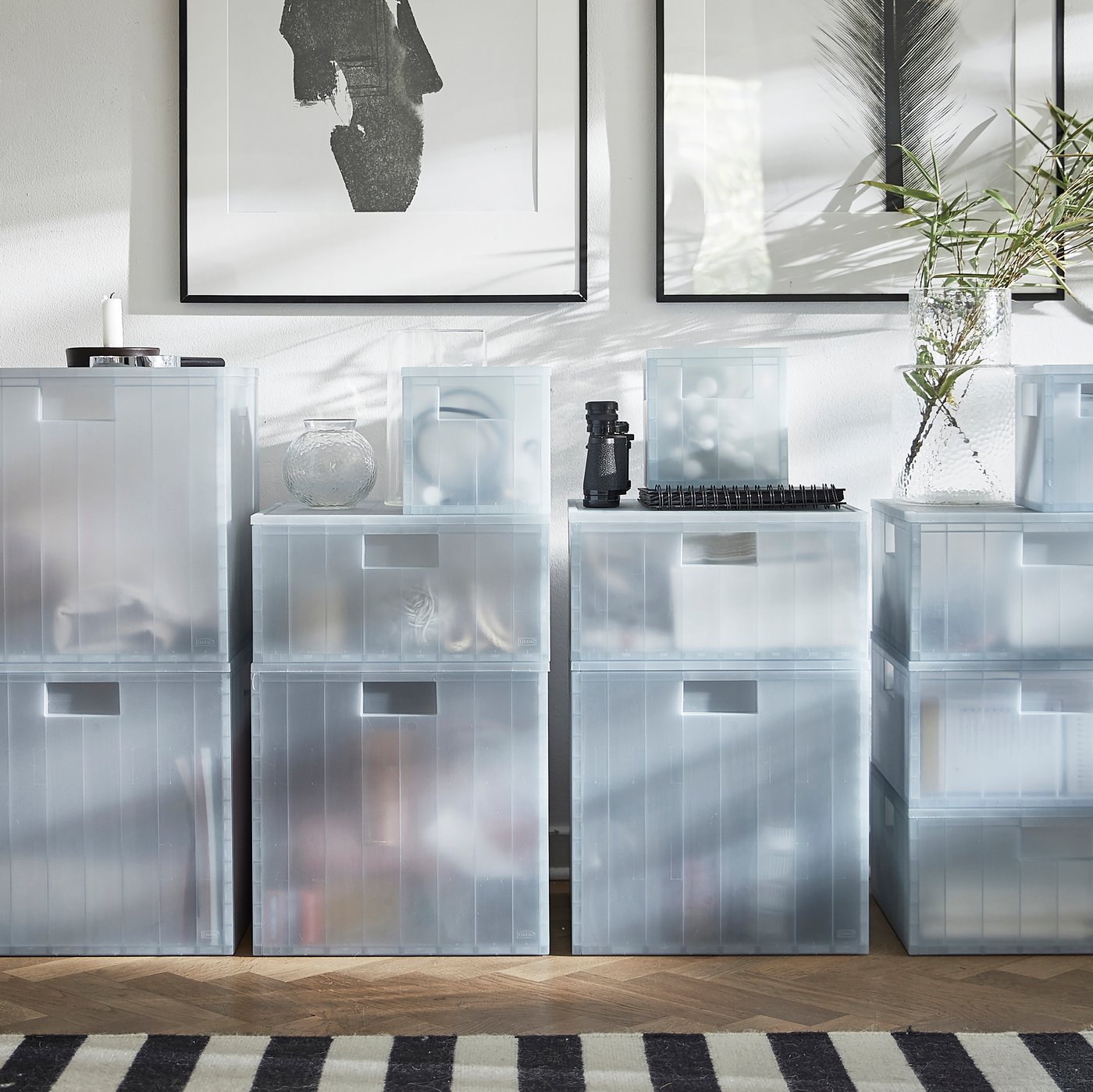A front view of different size of PANSARTAX storage boxes with lid with posters in frames mounted on a wall above them.