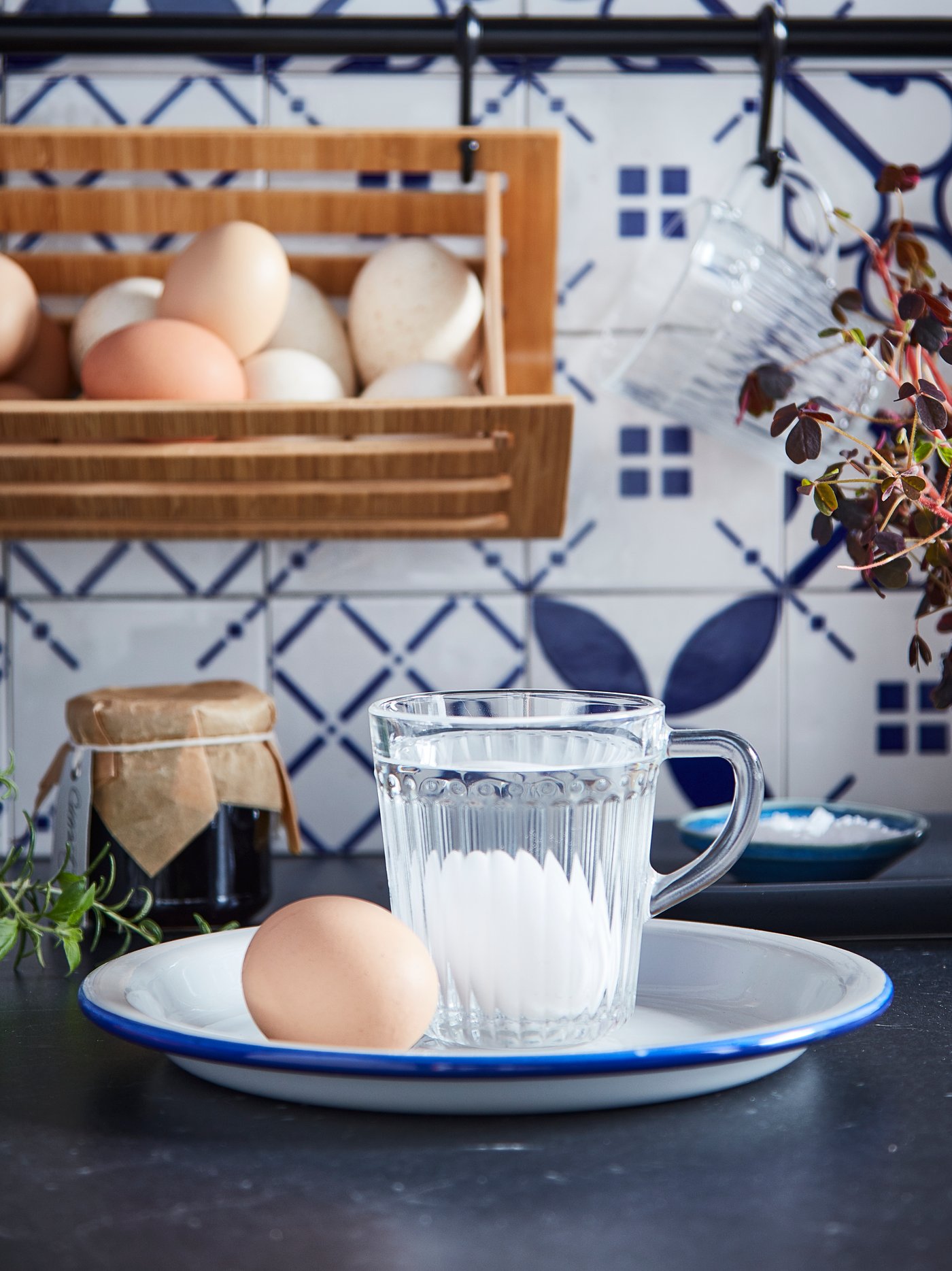 To æg på en tallerken, hvor det ene æg ligger på bunden af et DRÖMBILD krus af glas, som er fyldt med vand.