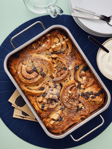 Pudding a base di girelle alla cannella KAFFEREP appena sfornato, in una teglia rettangolare, su una tovaglietta all'americana.