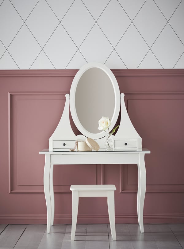 HEMNES vitt sminkbord med tillhörande spegel och pall vid en rosa vägg. 