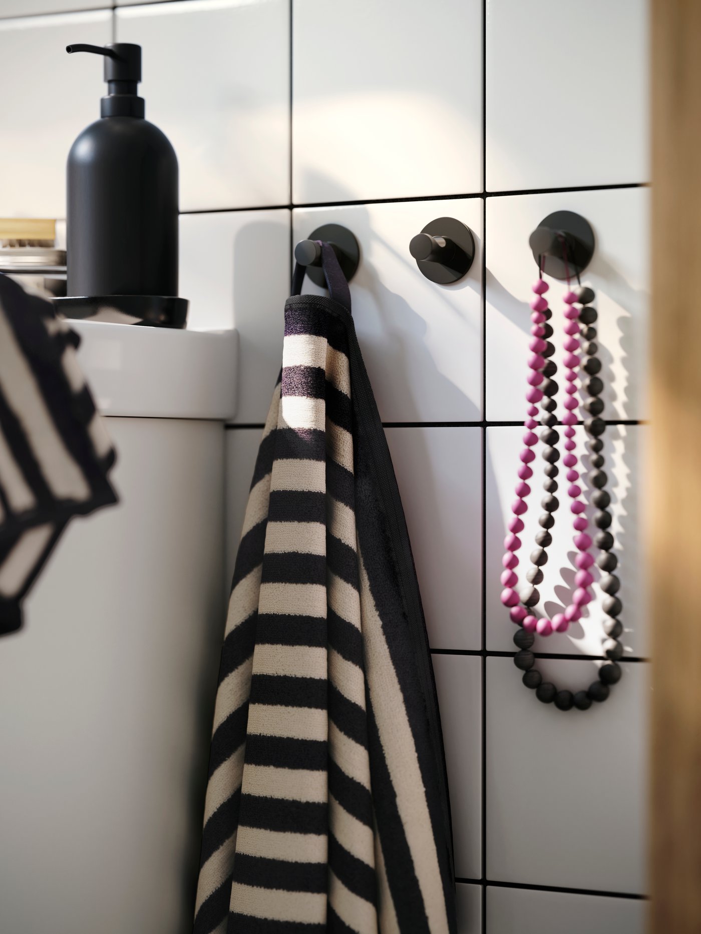 En vit- och svartrandig handduk hänger på en krok i ett badrum.
