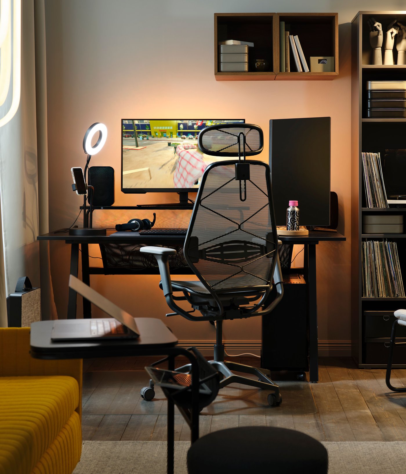 Unha configuración de xogos para PC brillante e retroiluminada ten un xogo en pausa nun monitor sobre unha mesa de xogos UTESPELARE negra xunto a unha cadeira de malla gris.