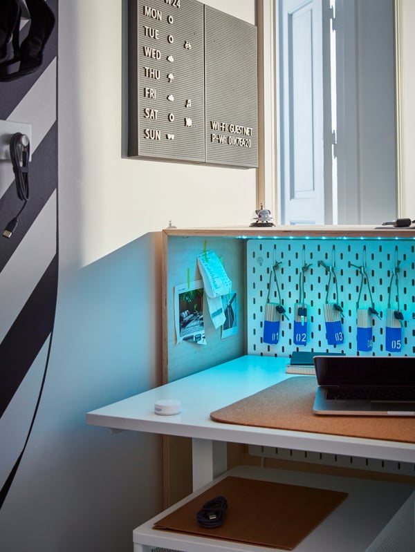 Behind the reception desk, showing a height adjustable desk with a laptop and a wall of keys to different rooms.