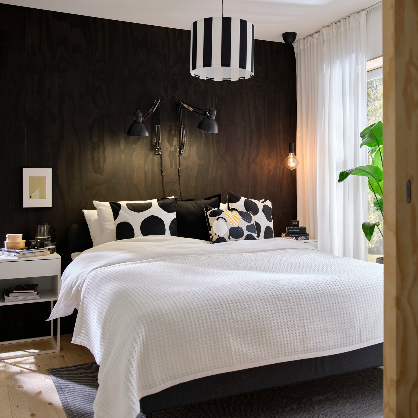 ÄNGSLILJA duvet cover in white washed cotton on double bed placed against dark wall with black lamps and sheer curtains.