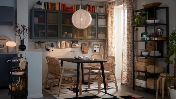 A dimly lit dining area formed by a black LISABO table and SALNÖ chairs and bench. On the wall are grey-green IVAR cabinets.