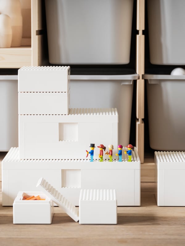 A pine FLISAT children’s table with built-in storage boxes holding BYGGLEK LEGO® bricks, plus two pine children’s stools.