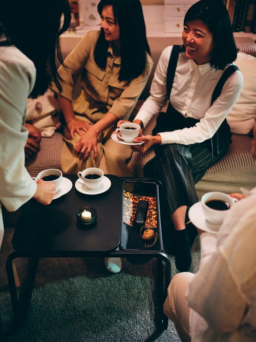 Cameră de zi cu 4 persoane așezată în jurul unei mese laterale dreptunghiulare ENHET, care bea din 4 cești de cafea și farfurioare VÄRDERA.