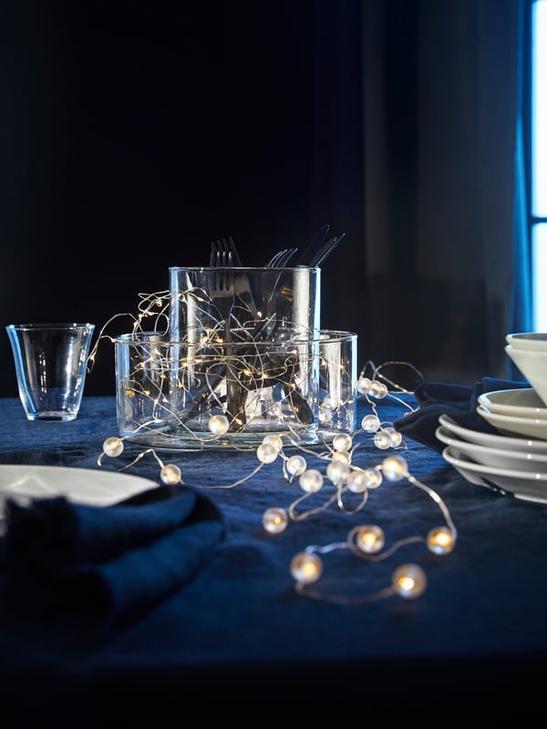 Una guirnalda luminosa encendida colocada en el centro de una mesa con mantel azul.