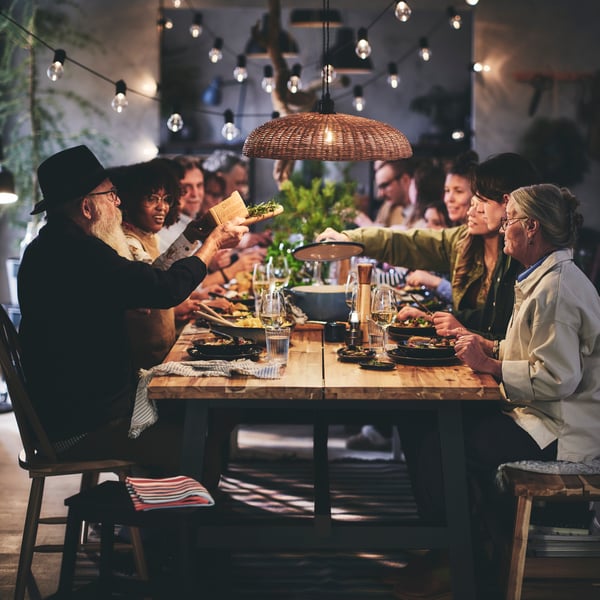 Un couple âgé assis au bout d'une longue table, entouré de convives de tous âges.