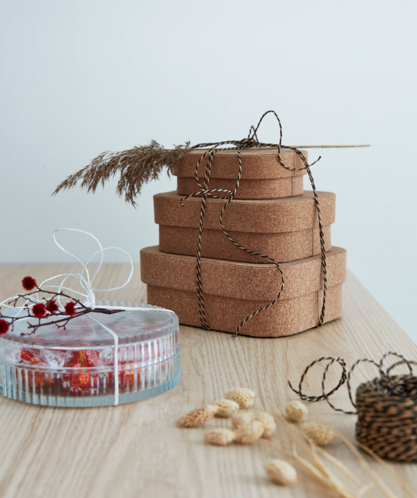 A stack of cork SAMMANHANG boxes with a lid and a SAMMANHANG glass box filled with candy.