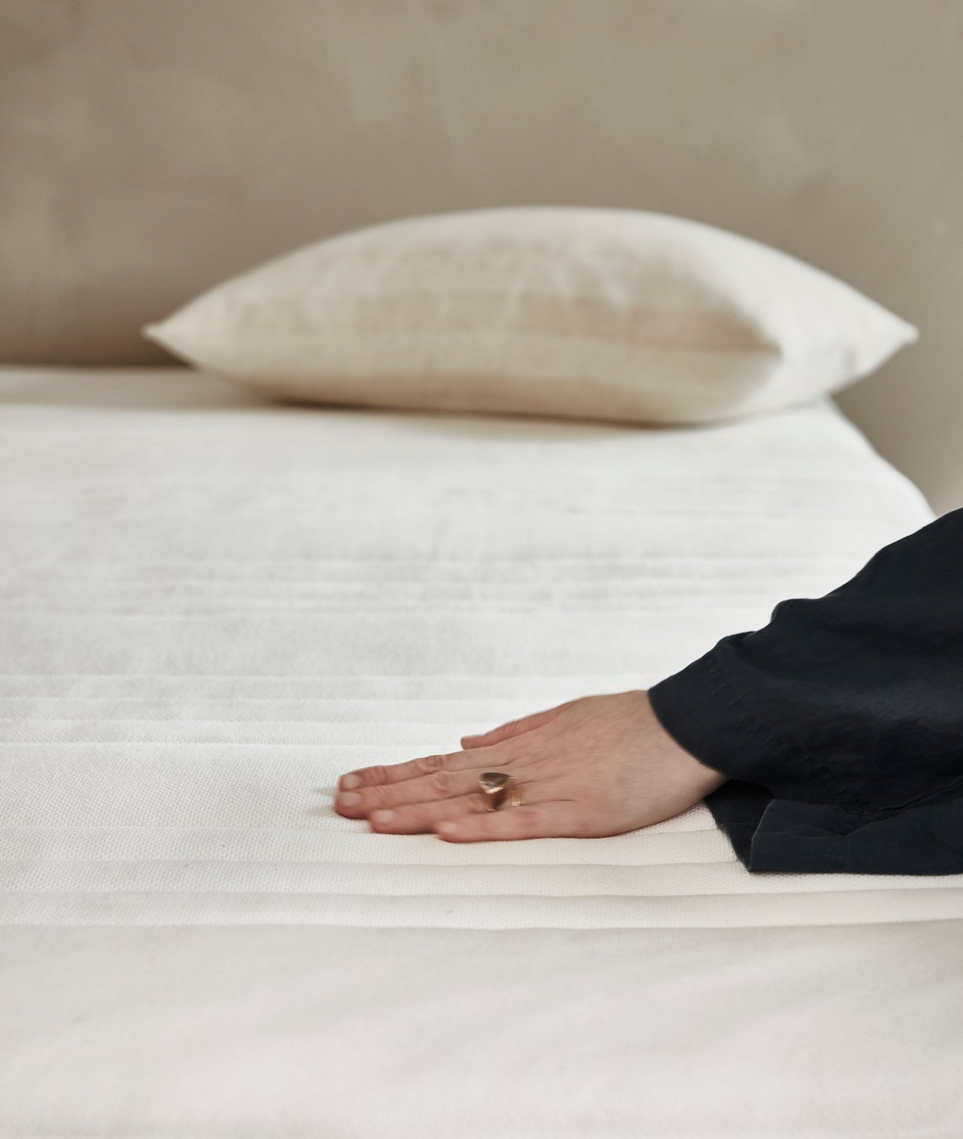 Udsnit af person der fører hånden over en topmadras