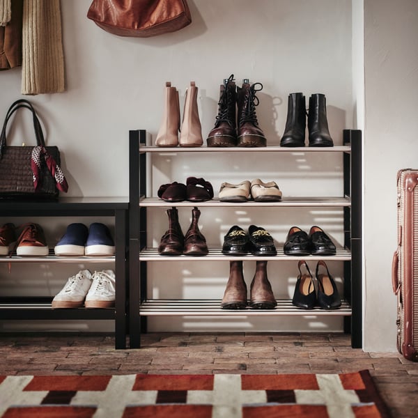 TJUSIG storage bench in black, next to two shoe racks with one stacked on top of the other. Shoes in neat order on shelves.