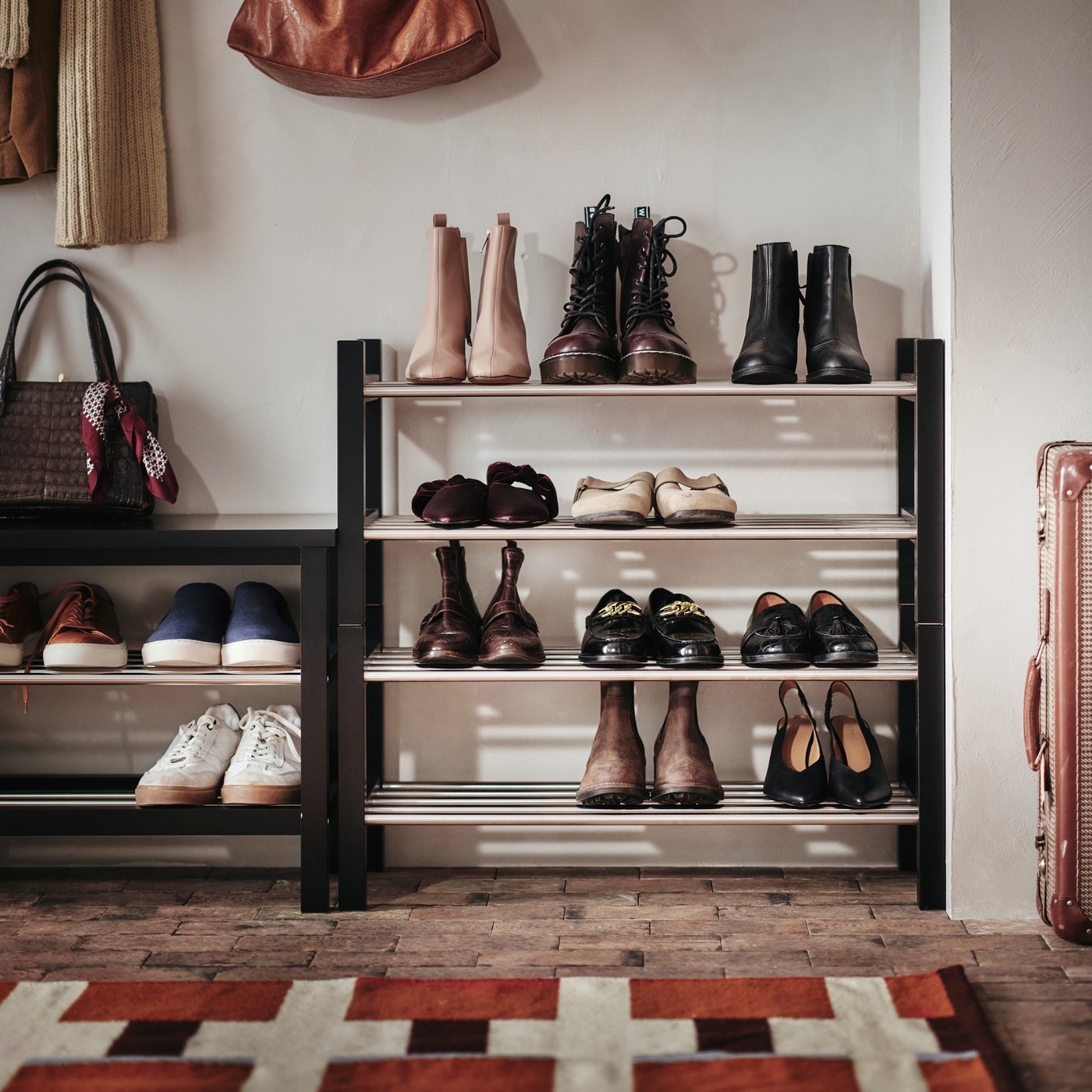 TJUSIG storage bench in black, next to two shoe racks with one stacked on top of the other. Shoes in neat order on shelves.