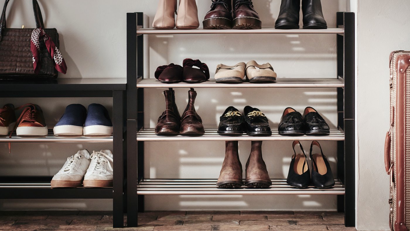 TJUSIG storage bench in black, next to two shoe racks with one stacked on top of the other. Shoes in neat order on shelves.