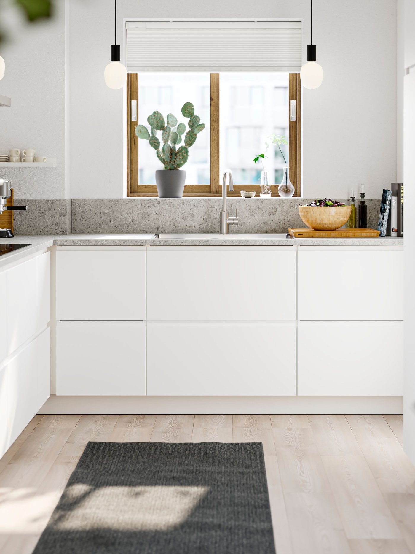 A matt white VOXTORP l shaped kitchen with light ash floors and a grey worktop