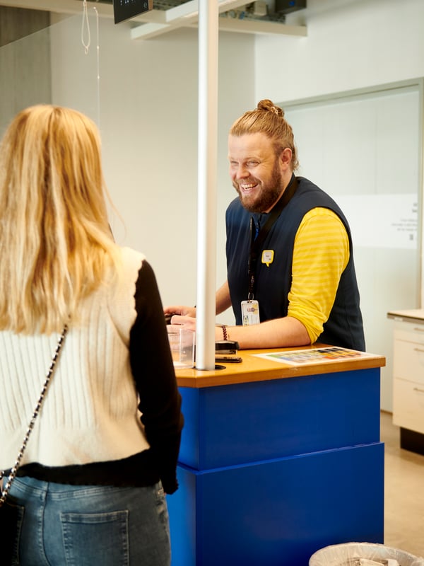 A woman collecting an order at the shop counter with an IKEA co-worker.
