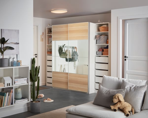 Helles Wohnzimmer mit weissen Möbeln neben einem grauen Sofa