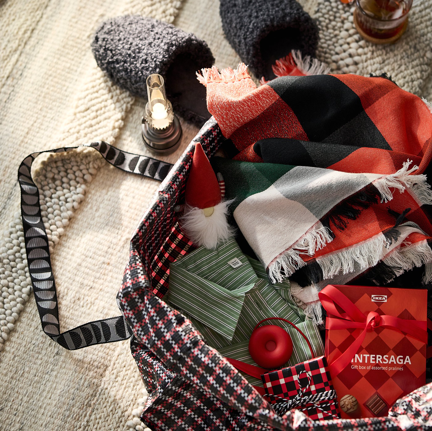 A VINTERFINT carrier bag filled with a VINTERFINT throw, a  box of VINTERSAGA pralines and items for a guest staying over
