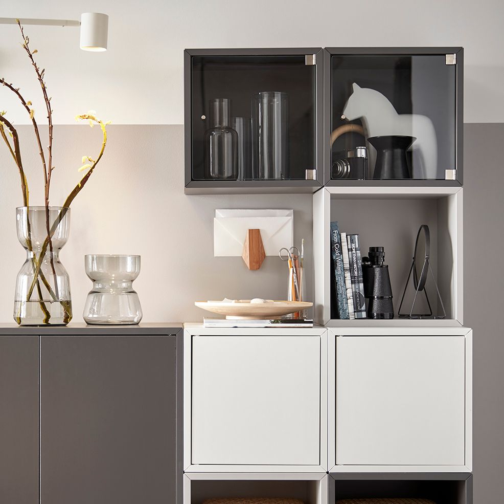 A living room with a dark grey EKET cabinet featuring two doors and a shelf, displaying decorative items.