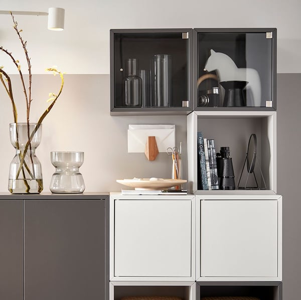 A living room with a dark grey EKET cabinet featuring two doors and a shelf, displaying decorative items.