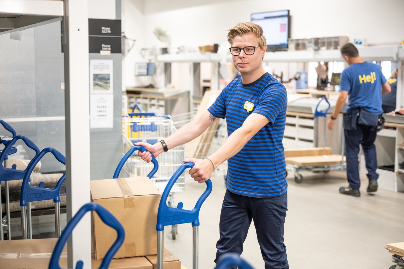 Collaborateur IKEA en train de déplacer un chariot plat avec des cartons dessus