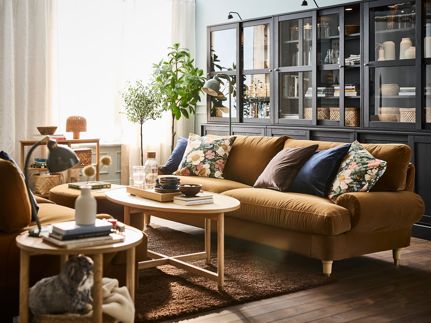 En stue med en brun 3-personers sofa, suppleret af et sofabord i træ og dekorative genstande.