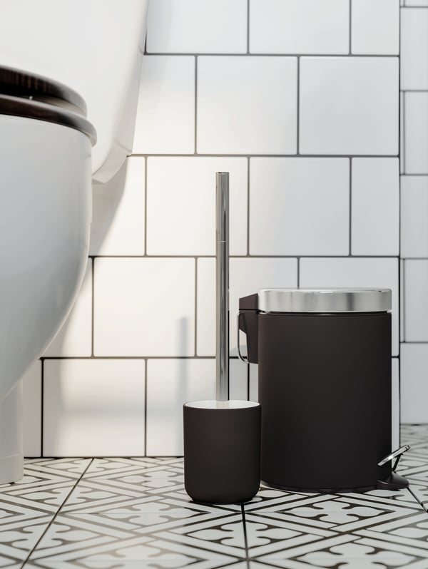 Accesorio de baño negro EKOLN junto a inodoro blanco.