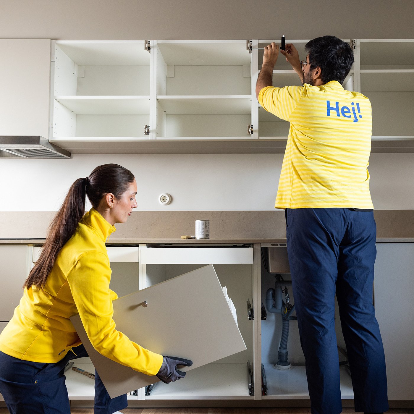 Two IKEA employees installing kitchen cabinets.